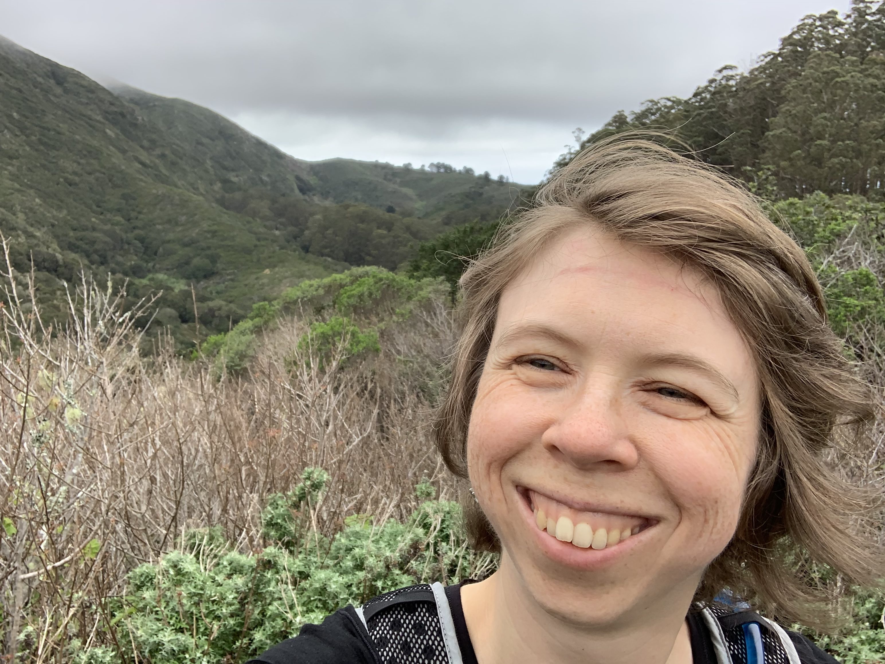 Liza in front of a beautiful coastal valley in the fog